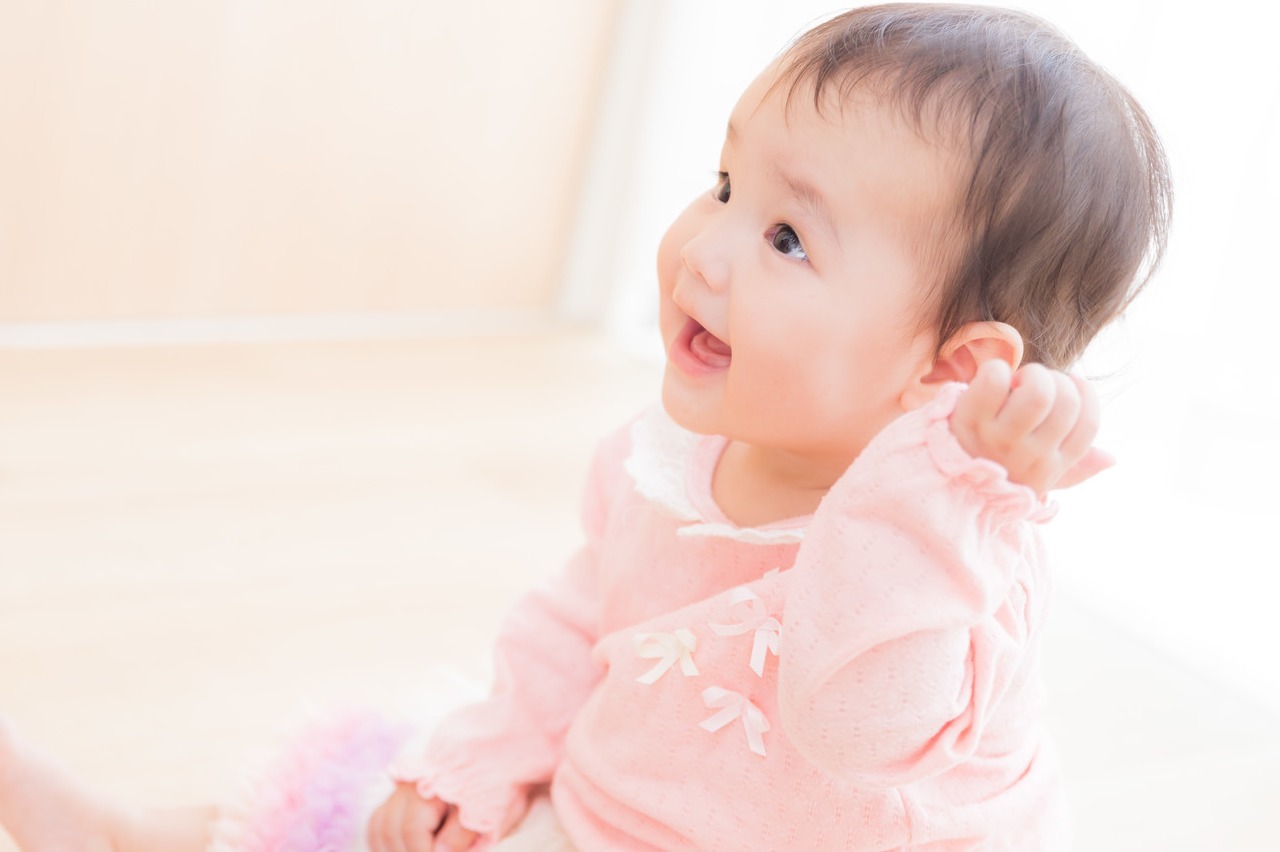 大人には見えない何かと笑顔で対話する赤ちゃんの画像