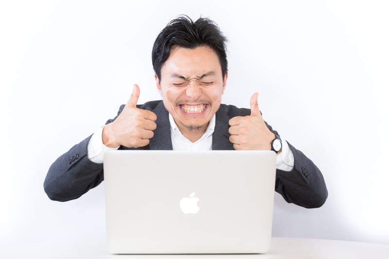 パソコンの前で喜ぶ人の画像