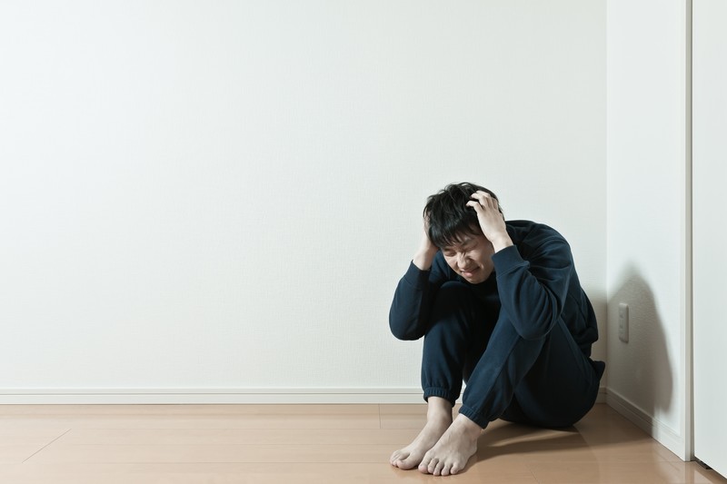 頭をかかえる悩める男性の画像