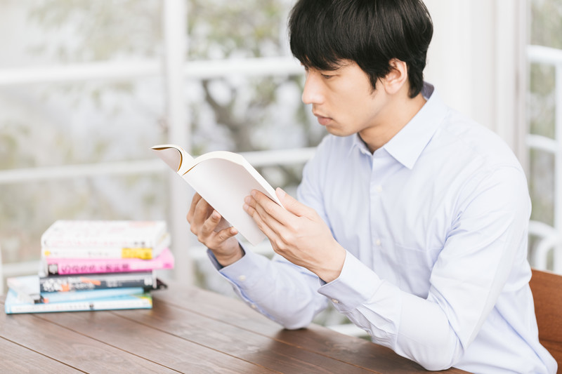 本を読んで勉強する男性の画像