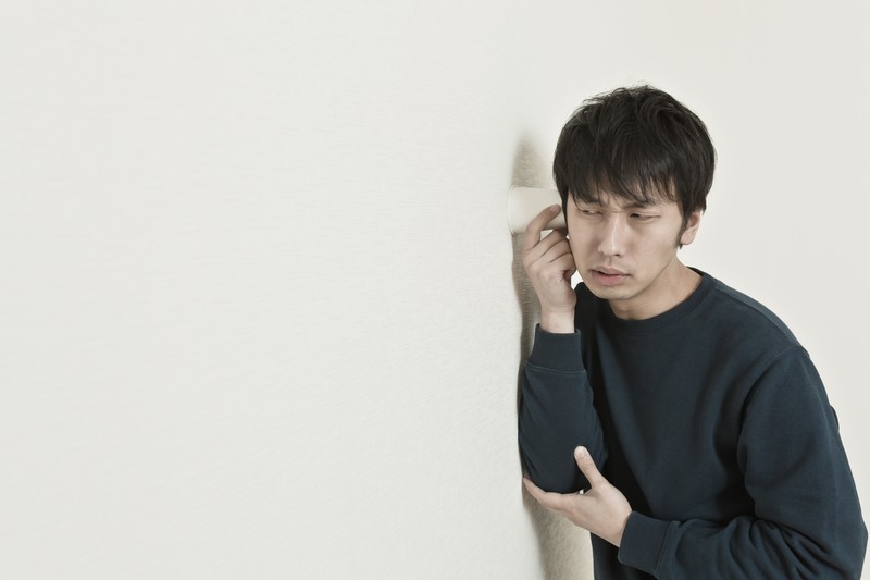 紙コップに耳をあて、盗み聞きしようとしている人の画像